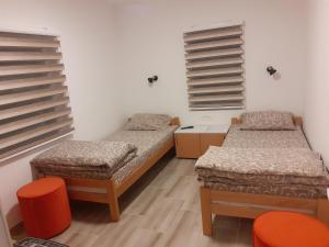 two beds in a room with two orange chairs at STD Cvetković in Crni Vrh