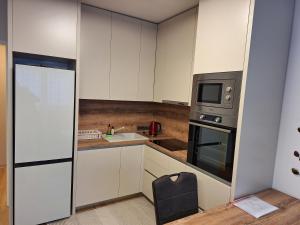a small kitchen with white cabinets and a black chair at Apartment Remi in Zagreb