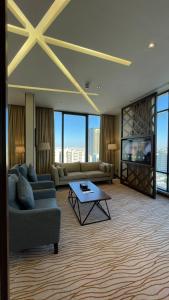 Rio Hotel Olaya في الرياض: غرفة معيشة مع كنب وتلفزيون وطاولة