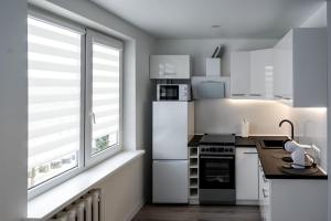 a kitchen with white appliances and a large window at Apartamentai in Marijampolė