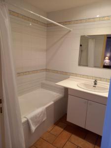 La salle de bains blanche est pourvue d'une baignoire et d'un lavabo. dans l'établissement Hotel de la Halle, à Nolay