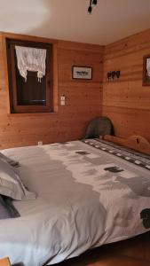 Cette chambre en bois comprend un grand lit et une fenêtre. dans l'établissement Chalet Coquelicot confort cosy au coeur du village de Saint Martin, à Saint-Martin-de-Belleville