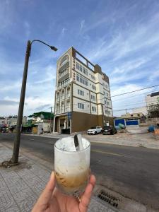 a person holding a drink in front of a building at Khách Sạn A68 in Vung Tau