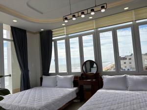 two beds in a room with large windows at Khách Sạn A68 in Vung Tau