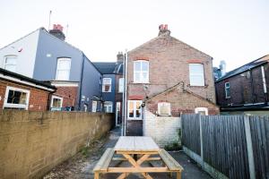 a wooden picnic table in front of a house at Dallow Rd Serviced Accommodation in Luton