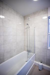 a white bathroom with a tub and a shower at Dallow Rd Serviced Accommodation in Luton