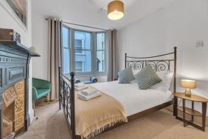 ein Schlafzimmer mit einem schwarzen Bett und einem Kamin in der Unterkunft Seaside Sanctuary House By My Getaways in Brighton & Hove