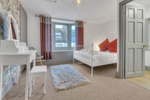 - une chambre blanche avec un lit bébé et un bureau dans l'établissement Seaside Sanctuary House By My Getaways, à Brighton et Hove
