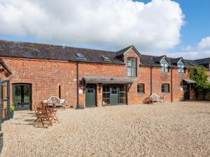 a brick building with tables and chairs in the courtyard at The Grain Store- Dex in Marshwood