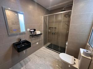 a bathroom with a shower and a sink and a toilet at La Bella Guesthouse in St. Julianʼs