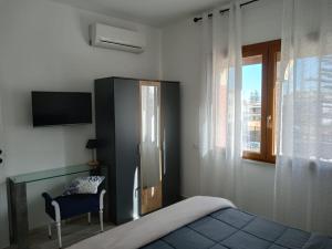 een slaapkamer met een bed, een stoel en een televisie bij La casetta di rosario mondello in Palermo