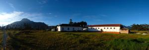 a building on a field with a mountain in the background at B&B Cotacachi Hosteria Oro Azul in Cotacachi