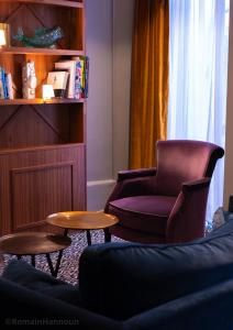 uma sala de estar com uma cadeira e duas mesas em Hotel Taylor em Paris