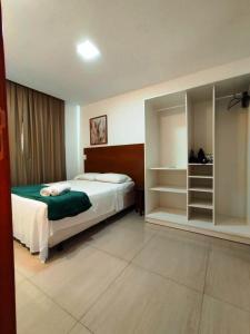 - une chambre avec un lit et une étagère dans l'établissement Apartamento aconchegante em condomínio perto da praia, à Ilhéus