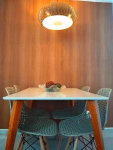 une table avec des chaises et une lampe sur un mur dans l'établissement Apartamento aconchegante em condomínio perto da praia, à Ilhéus