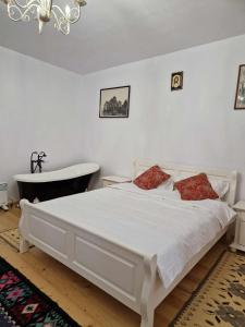 een slaapkamer met een wit bed en een bad bij Casa Veche in Neagra Şarului