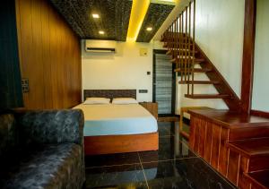 a bedroom with a bed and a staircase and a couch at JC Den Kochi Villas by VOYE HOMES in Cochin