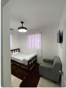 ein kleines Schlafzimmer mit einem Bett und einem Stuhl in der Unterkunft residencial garcia I apt 4 in La Romana