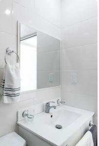 ein weißes Badezimmer mit einem Waschbecken und einem Spiegel in der Unterkunft residencial garcia I apt 4 in La Romana