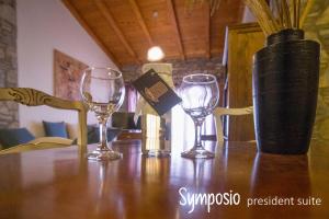 tres copas de vino sentadas en una mesa de madera en Pyrgos Traditional Village, en Agios Kirykos