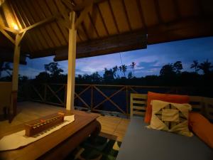 Zimmer mit Sofa und Tisch auf der Veranda in der Unterkunft Babahan Farmstay in Tabanan