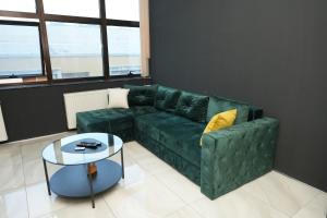 a living room with a green couch and a table at Diamond Apartments Niš in Niš