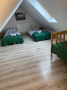 two beds in a attic bedroom with wooden floors at Apartament Nasze Poddasze in Ciche