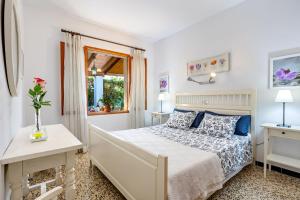 a white bedroom with a bed and a window at Casa La Palmera in Cala Figuera