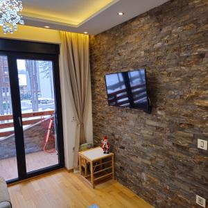 uma sala de estar com televisão numa parede de pedra em Apartman Pineta em Zlatibor