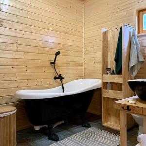 a bath tub in a bathroom with a wooden wall at Drewniany dom na skraju lasu U Pana Szeptuna in Lidzbark