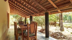 un porche con mesa de madera y sillas en Très agréable maison 2 chambres avec jardin, en Abémé