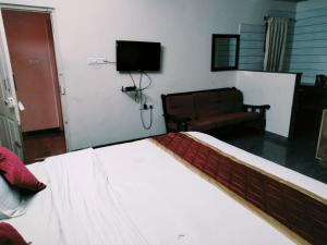 een slaapkamer met een bed, een bank en een televisie bij Urban Express G Grand in Bangalore
