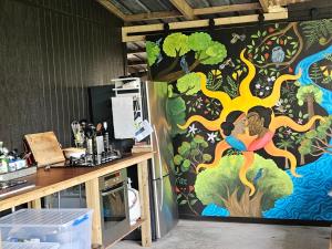a wall with a painting of a tree on it at Forest Waters Bungalow in Haruru