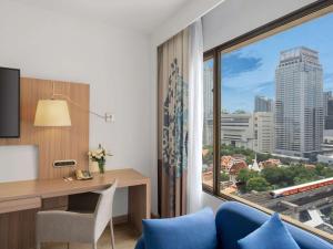 a hotel room with a desk and a large window at Novotel Bangkok on Siam Square in Bangkok