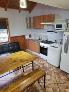 a kitchen with a wooden table and a stove at Aysen Bike Cabañas in Puerto Aisén