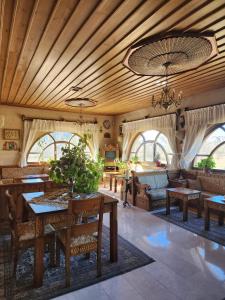 Hotel Kral Boutique في أوروغوب: غرفة معيشة بسقوف خشبية وطاولات وأريكة