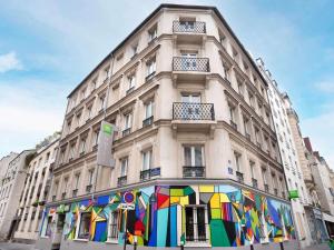 un grand bâtiment avec une fresque colorée sur son côté dans l'établissement ibis Styles Paris Maine Montparnasse, à Paris