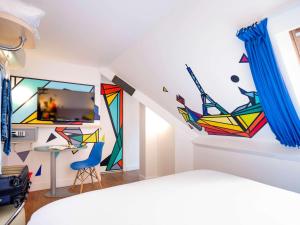 パリにあるイビス スタイルズ パリ メーヌ モンパルナスのベッドルーム1室(壁に絵画が飾られた部屋1室)