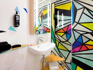 パリにあるイビス スタイルズ パリ メーヌ モンパルナスのカラフルな壁のバスルーム(シンク付)