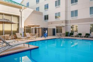 una piscina en un hotel con sillas y sombrillas en Hilton Garden Inn El Paso Airport en El Paso