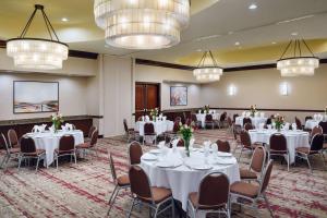 una sala de banquetes con mesas y sillas blancas y lámparas de araña en Hilton Garden Inn El Paso Airport, en El Paso