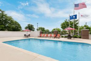 - une piscine avec des chaises longues et des parasols dans l'établissement Hilton Garden Inn Greenville, à Greenville