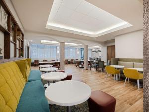 a waiting room with tables and chairs and a couch at Hampton Inn West Palm Beach-Florida Turnpike in West Palm Beach