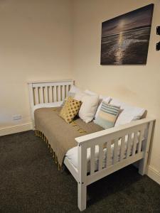 een slaapkamer met een wit bed met kussens erop bij cleethorpes seaside garden apartment in Cleethorpes