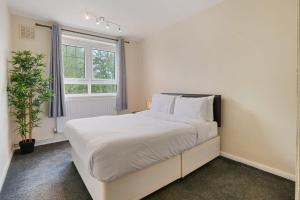 a white bedroom with a large bed and a window at The Serene Flat W Free Street Parking in Hackbridge