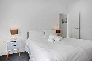a white bedroom with a white bed and a night stand at Victoria House Near Beach With Free Parking in Southend-on-Sea