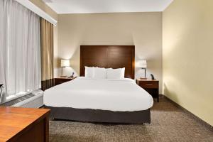 a hotel room with a large bed with white sheets at Comfort Inn New Orleans Airport South in Saint Rose +26 photos