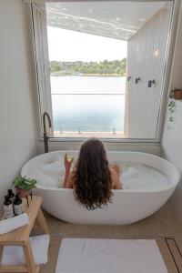 a woman laying in a bath tub in a room with a window at Edge Luxury Villas in Wilyabrup