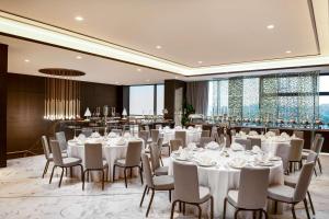 科威特Waldorf Astoria Kuwait的一个带白色桌椅的宴会厅和一间酒吧