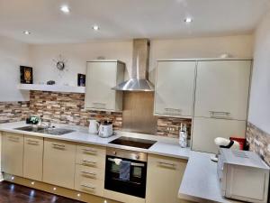 una cocina con armarios blancos y fregadero en Theodora Suite 3 - Free Parking, en Kent